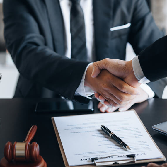 Two professionals shaking hands over a signed agreement